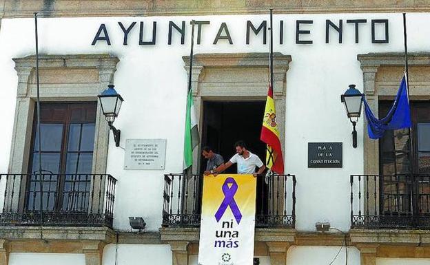 Dos personas colocan un cartel que reclama el fin de la violencia machista en el Ayuntamiento.