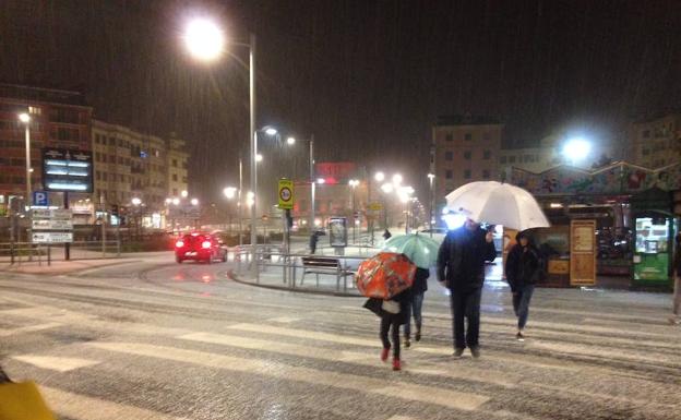 Viandantes cruzan un paso de cebra en el Paseo Colón en plena granizada.