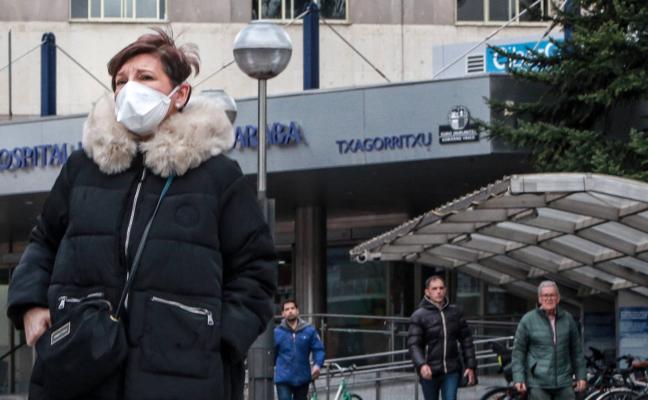 Una mujer se protege con una mascarilla en el exterior del Hospital Txagorritxu, donde se controla un posible foco de infección por coronavirus./Rafa Gutiérrez