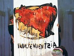 Una joven escribe la palabra "independentzia" bajo el mapa que suman los territorios de País Vasco, Navarra y parte de Francia, durante el mitin que ANV celebró ayer en Pamplona para presentar a sus candidatos al Congreso en las próximas elecciones generales del 9 de marzo. /EFE/