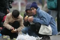 Grupo de indigentes alimentándose de restos de comida en la calle./