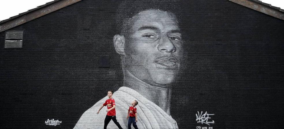 Dos niños con la camiseta del Manchester United, ante el mural de Rashford en Withington. / AFP