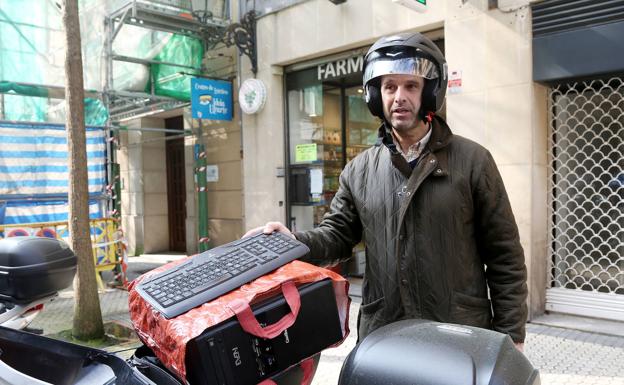 Alvaro, en la calle Garibay, mete el ordenador en la moto para teletrabajar en casa los próximos días.