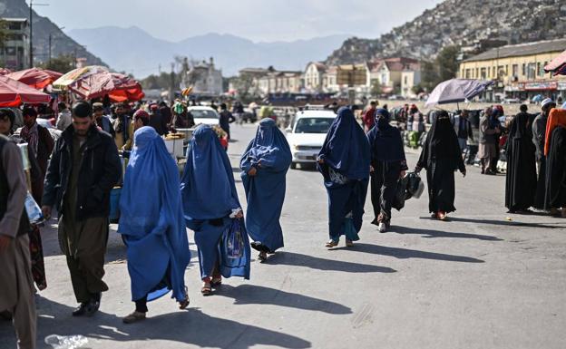 A group of women walk through a street market in Kabul.
