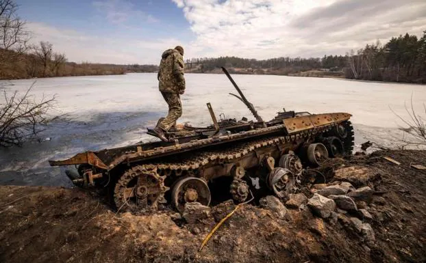 A Ukrainian soldier looks at the damage to an armored vehicle hit by a missile in the town of Trostianets.