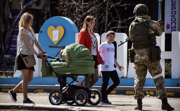 A Russian soldier guards a street in the self-proclaimed Donetsk People's Republic as a family watches. 