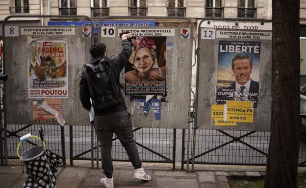 French street artist Jaeraymie pastes an election poster depicting a caricature of 'Les Republicains' during the elections.