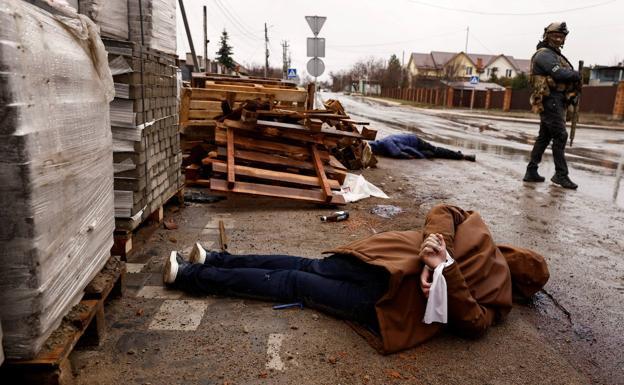 The body of a man with his hands tied behind his back lies on the ground in a street in Bucha.
