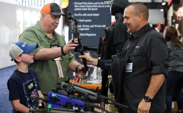 A man holds a pistol conversion kit next to a boy during the convention that kicked off Friday.