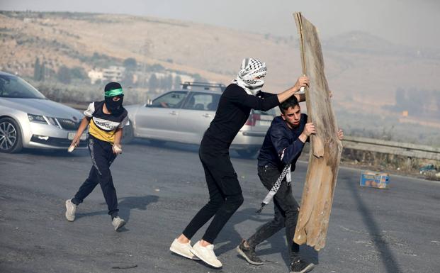 Several Palestinian civilians face the Israeli forces near Nablus, protecting themselves with a cardboard sheet.
