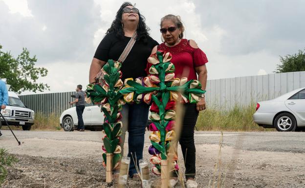Two women place crosses and candles at the site where dozens of migrants were found dead inside a truck in Texas.