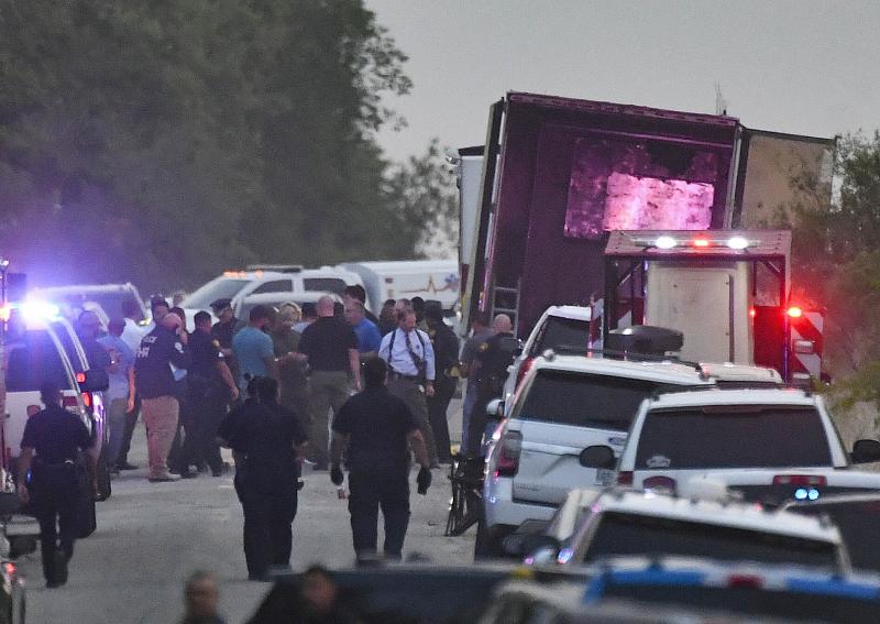 Police and coroners work on the truck full of migrants that was abandoned on a Texas highway.