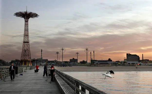 A group of people walk along the historic Coney Island boardwalk. 