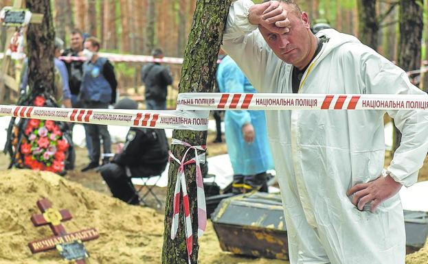 An emergency service worker rests during exhumation work in Izium 