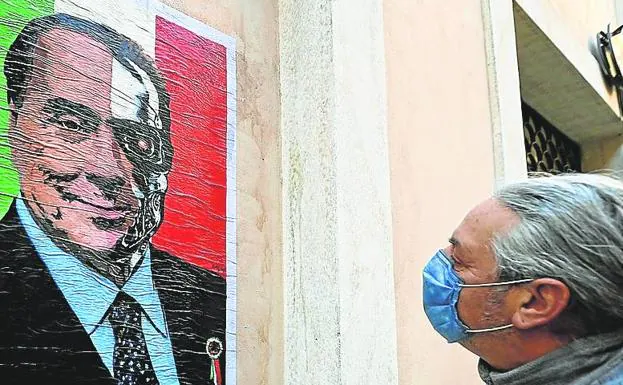 A citizen observes a poster of veteran Silvio Berlusconi.