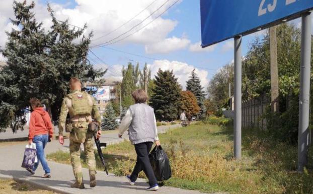 A Russian soldier escorts two civilians to a polling point during the referendums for the annexation of the occupied territories to Russia.