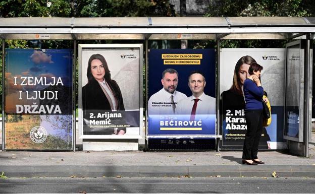 A woman waits at a Sarajevo bus stop where election propaganda is displayed. 