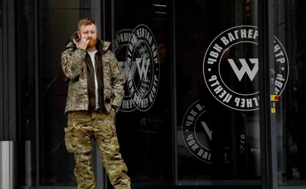 A man dressed in military camouflage stands at the entrance to the new headquarters of the Wagner group during the official opening of the office block in Saint Petersburg. 