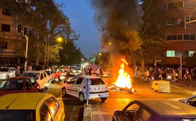 A group of protesters set fire to a police motorcycle during a day of protests in Tehran. 