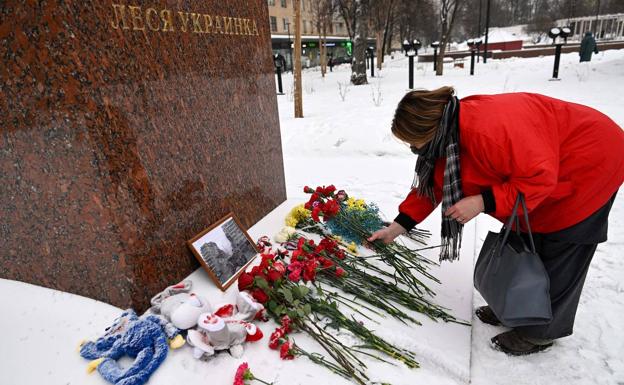 A woman leaves flowers at the foot of a statue to remember the victims of Dnipro in Moscow